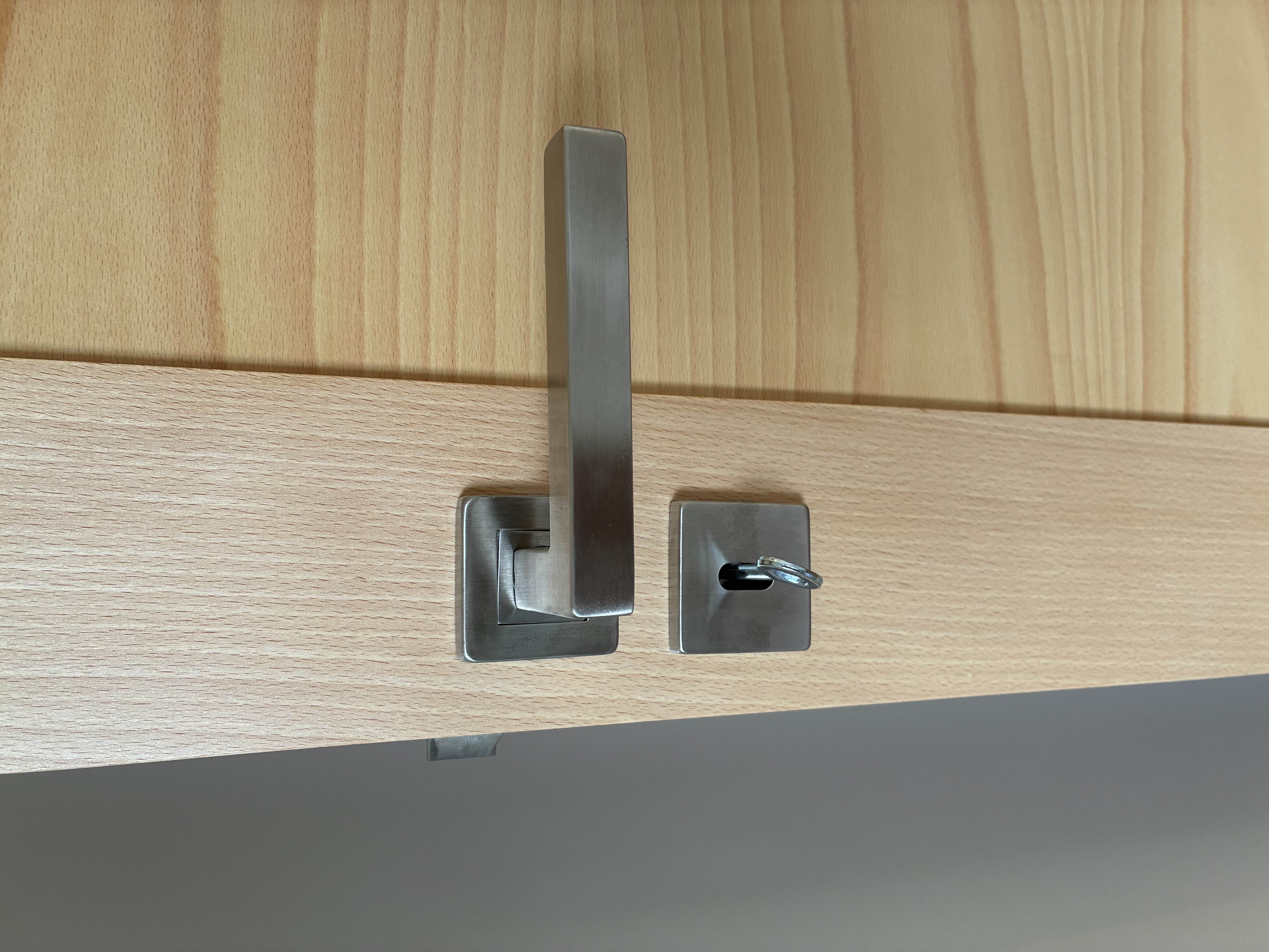 Béquille Hoppe Toulon en inox montée sur rosace, avec rosace de clé, sur porte en hêtre